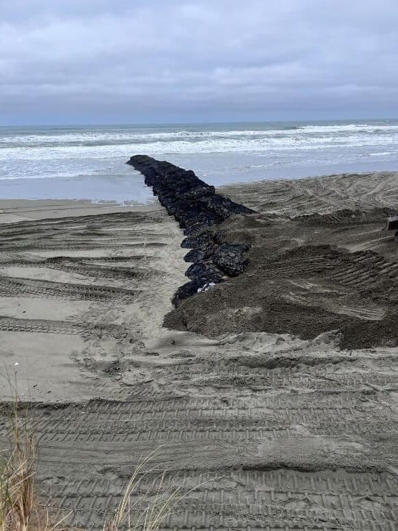 Rock bags laid across a beach to the waterline
