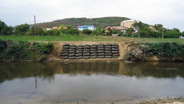 A row of rock bags along a river bank